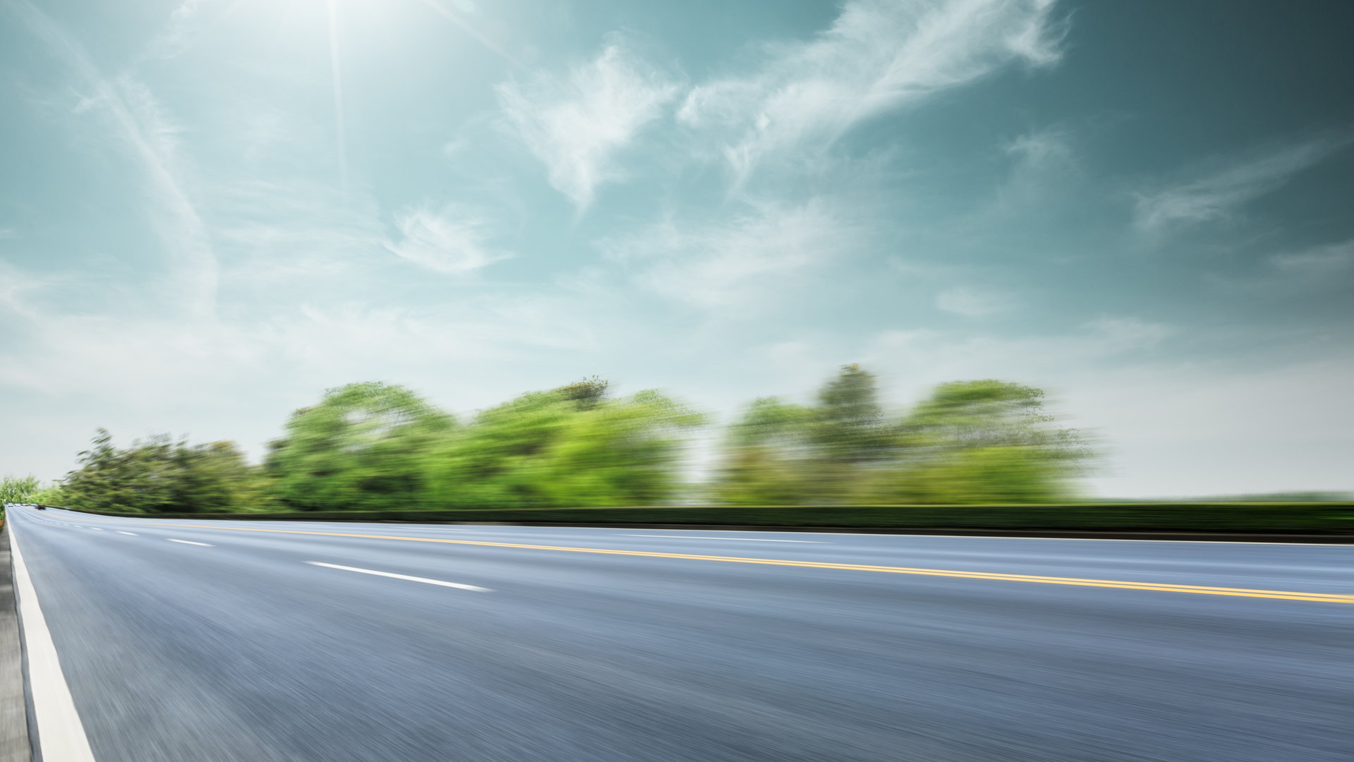 Open Road With Sunlight and Green Shoulders